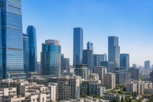 日中のアジア都市に複数の高層オフィスが並ぶ風景